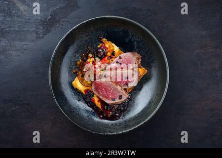 Traditional roasted Italian panettone tagliata di manzo with sliced beef steak and vegetable served as top view on a Nordic desi Stock Photo