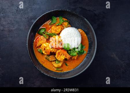 Traditional Thai kaeng phet red curry with chili and basmati rice served as top view in a Nordic design bowl with copy space Stock Photo
