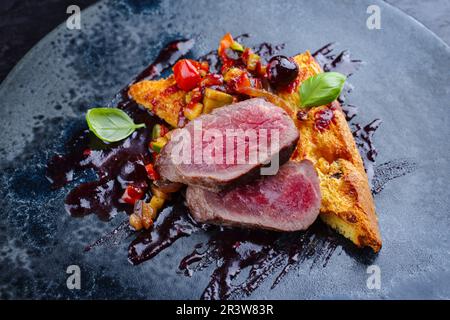 Traditional roasted Italian panettone tagliata di manzo with sliced beef steak and vegetable served as close-up on a Nordic desi Stock Photo