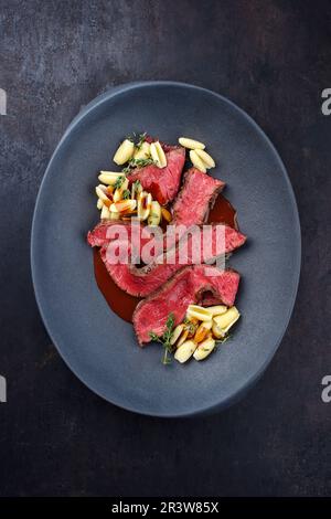 Traditional Italian chianina sliced roast beef with gnocchetti sardi pasta in spicy red wine sauce served as top view in a desig Stock Photo
