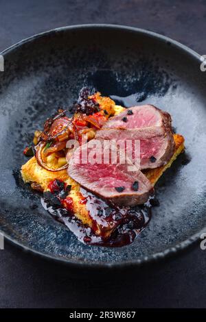 Traditional roasted Italian panettone tagliata di manzo with sliced beef steak and vegetable served as close-up on a Nordic desi Stock Photo