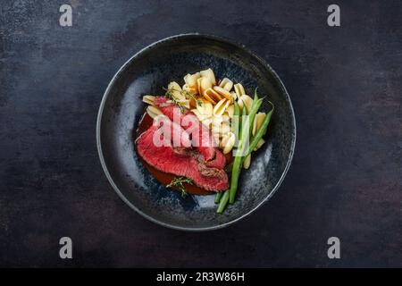 Traditional Italian chianina sliced roast beef with gnocchetti sardi pasta and beans in spicy red wine sauce served as top view Stock Photo