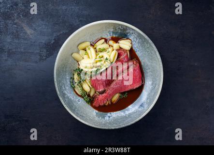 Traditional Italian chianina sliced roast beef with gnocchetti sardi pasta in spicy red wine sauce served as top view in a Nordi Stock Photo