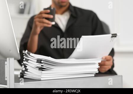 Man drinking coffee while working with documents at table in office, closeup Stock Photo
