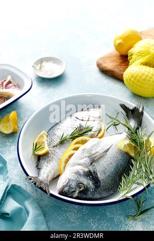 Fresh raw dorado fish cooking with lemon and rosemary. Sea bream, dorado. Seafood, healthy food Stock Photo