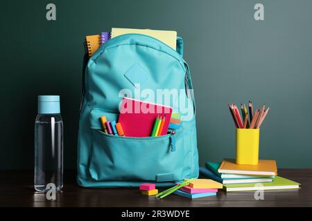 Backpack with different school stationery on white table near chalkboard Stock Photo