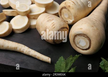 Whole and cut parsnips on wooden board, closeup Stock Photo