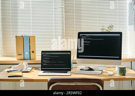 Horizontal image of computers with security codes on the screen standing on workplace of programmer in office Stock Photo