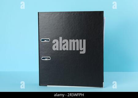 Black hardcover office folder on light blue background Stock Photo