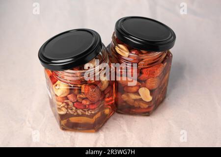 Jars with different nuts and honey on beige background Stock Photo