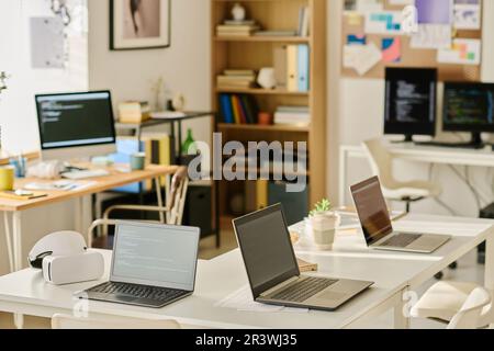 Horizontal image of modern IT office with computers on workplaces of programmers Stock Photo