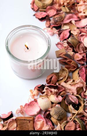 photo of a pink dried plant and a burning candle on a white background Stock Photo