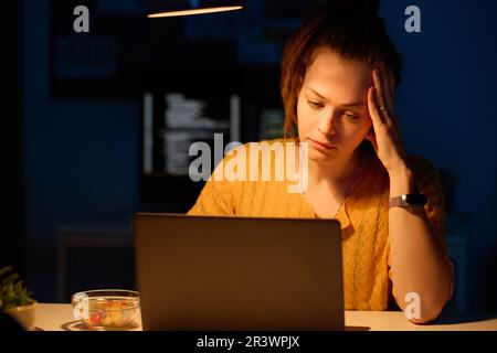 Young tired programmer working on computer in office till late night Stock Photo