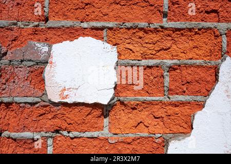 Brick wall with pieces of old peeling off white plaster Stock Photo