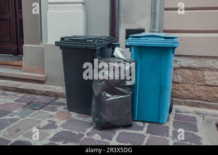 A large and small blue trash can near cafe on a city street. Sorting garbage by material and type. Environmental protection, ecology. High quality Stock Photo