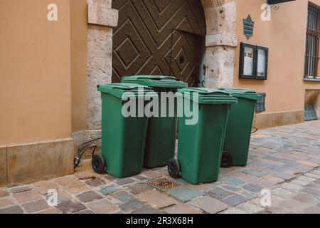 A large and small green trash can near cafe on a city street. Sorting garbage by material and type. Environmental protection, ecology. High quality Stock Photo