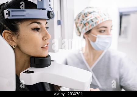 Woman sitting at an x-ray machine in a dentist's office attended by a specialist Stock Photo