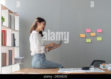 business woman pleased happy cheerful cute beautiful business woman sit in office using laptop computer Stock Photo