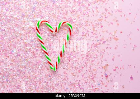 Two lollipops in heart shape on pink background with glitter. Gifts for the New year and Christmas. top view Stock Photo