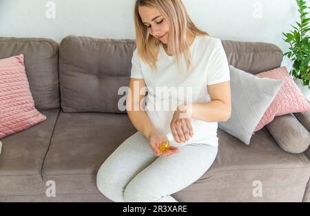 Pregnant woman drinks omega three. Selective focus. White. Stock Photo