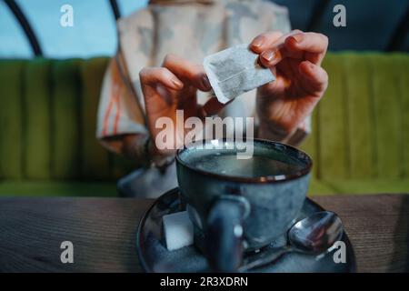 Woman brewing a fresh mug of tea with teabag in cafe Stock Photo