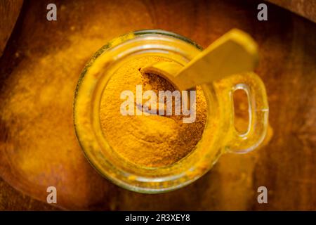 ground turmeric in a glass jar on wooden background. Stock Photo