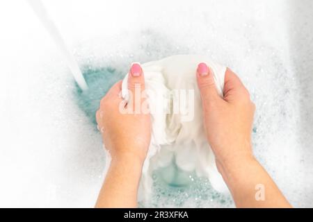 Wash clothing by hand with whitening detergent in laundry sink Stock Photo