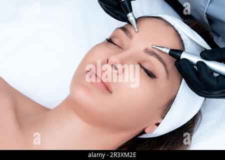 Cosmetology. Beautiful Woman At Spa Clinic Receiving Stimulating Electric Facial Treatment From Therapist. Closeup Of Young Fema Stock Photo