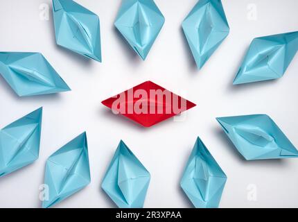 A group of blue paper boats surrounded one red boat, the concept of bullying, search for compromise. Stock Photo