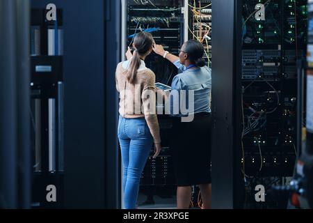 Server room, engineer and women team with tablet for programming, cybersecurity or cable maintenance. Female technicians together in datacenter for Stock Photo