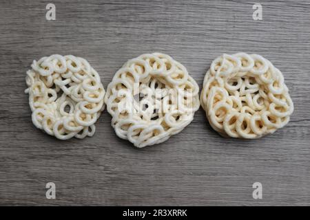 Kerupuk or kerupuk warung is Indonesian traditional deep fried crackers made from starch mixed with flavors such as fish, on a wooden table. Selective Stock Photo