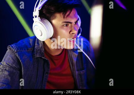 Gamer staring at the computer screen with an expression of shock and disbelief, trying to get a closer look at what he’s seeing in this intense moment Stock Photo