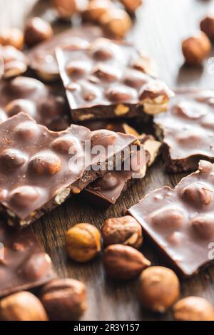 Broken chocolate bars with  nuts on the wooden table. Stock Photo