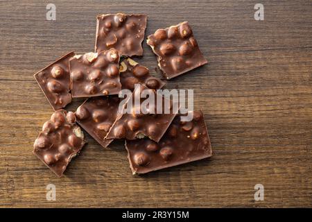 Broken chocolate bars with  nuts on the wooden table. Top view. Stock Photo