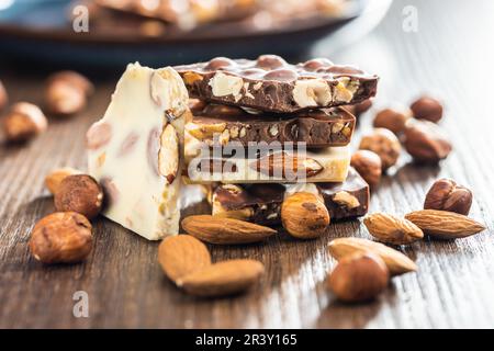 Broken chocolate bars with  nuts on the wooden table. Stock Photo
