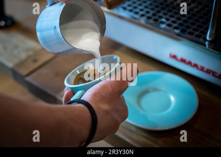 Pouring hot milk into a cup for latte art as a home Barista making a morning drink, closer detail shots Stock Photo