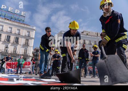 Madrid, Spain. 25th May, 2023. Protesters perform as if they are putting out a fire during the demonstration. Forest Firefighters of the Public Service of Madrid Community protest in Puerta del Sol Madrid, in front of the Regional Headquarters Government building demanding decent working conditions and for the defense of their rights and compliance with labor legislation. Credit: SOPA Images Limited/Alamy Live News Stock Photo