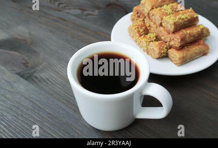 Closeup of a Cup of Turkish Coffee with Blurry Baklava Pastries in the Backdrop Stock Photo