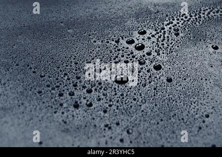 Drops of water on a dark matte surface close up, water blots, design concept from water on a matte background, macro photo of drops, glare in water Stock Photo