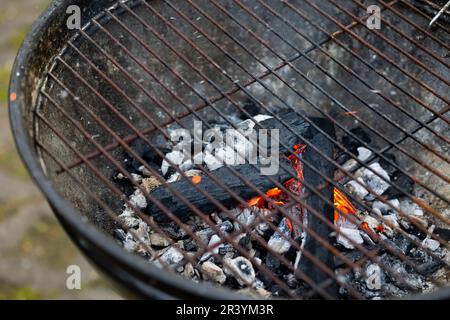 Hearth of a metal grill with glowing charcoal flame. Preparation for barbecue in the garden. Stock Photo