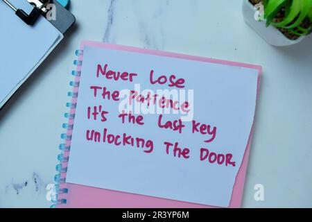 Concept of Never Lose The Patience It's The Last Key Unlocking The Door write on sticky notes isolated on Wooden Table. Stock Photo