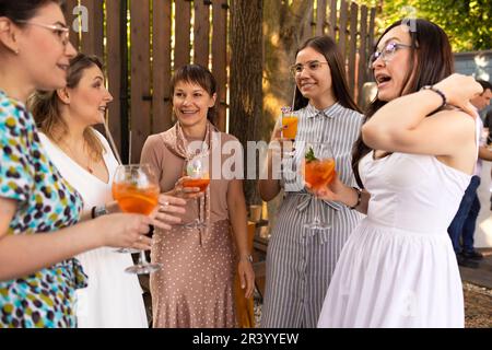 Happy female friends spending time together, young woman drinking Aperol spritz Stock Photo
