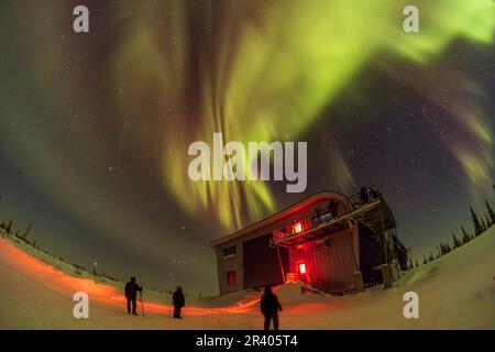 Observers watching a dim aurora over the Churchill Northern Studies Centre, in Churchill, Manitoba, Canada. Stock Photo