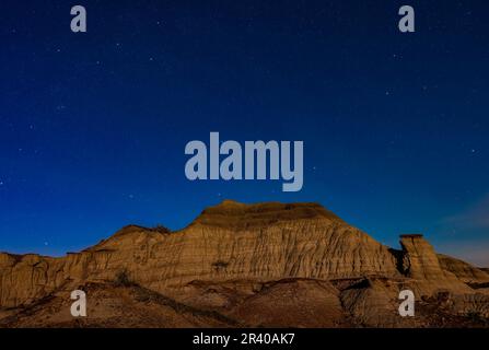 Andromedia, Cassiopeia and Pegasus rising over moonlit formations at Dinosaur Provincial Park. Stock Photo