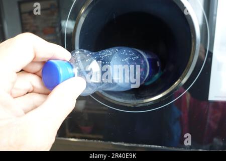 Symbolic image return machine for PET deposit bottles - man's hand throws a PET bottle into a machine Stock Photo