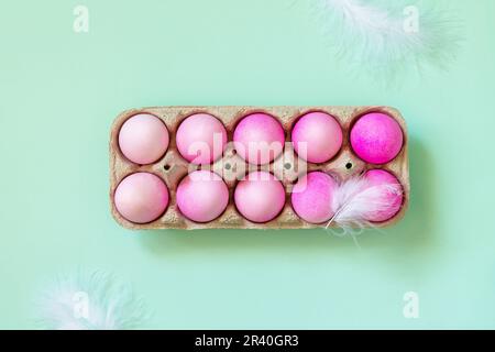Minimal Easter concept. Easter elements, paper box with eggs in pink colors on pastel green background. Top view flat lay. Stock Photo