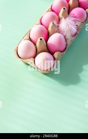Minimal Easter concept. Easter elements, paper box with eggs in pink colors on pastel green background. Copy space. Stock Photo