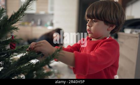 One little boy decorating Christmas tree. Closeup child putting ball decoration Stock Photo