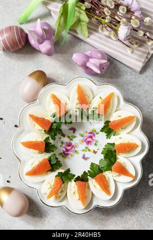 Stuffed eggs with cheese and salted salmon in the form of a carrot. Festive dinner, Easter brunch. View from above. Stock Photo