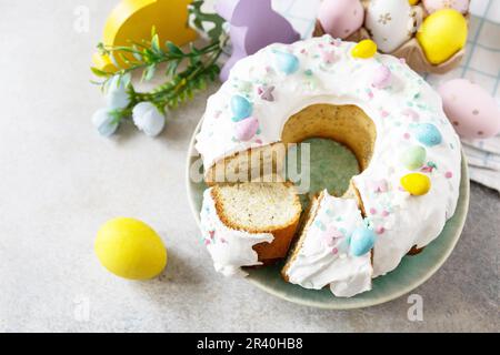 Happy Easter holidays, tasty dessert. Glazed easter lemon cake decorated with confectionery and mini chocolate eggs candy on gra Stock Photo